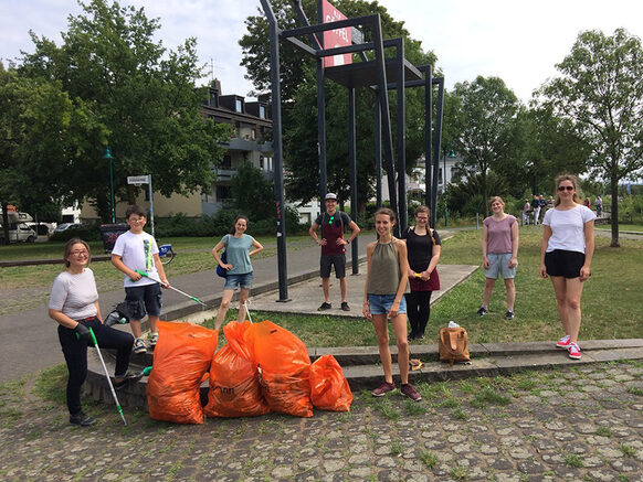 Eine Gruppe Menschen nach dem Müllsammeln mit orangefarbenen Müllsäcken