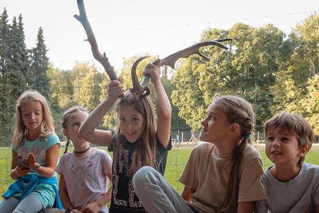 Kinder spielen mit einem abgefallenen Hirschgeweih.