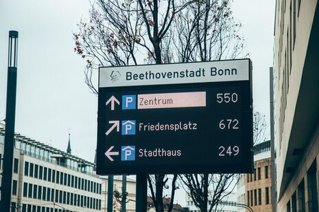 Eine Anzeigetafel neben einer Straße mit der Anzahl der freien Parkplätze in Bonner Parkhäusern.