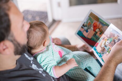Un padre guarda un libro illustrato con un bambino