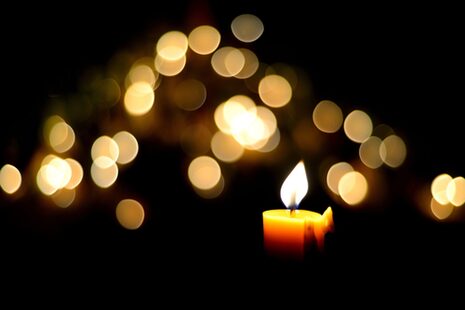 Una sola candela davanti a un mare di luci.