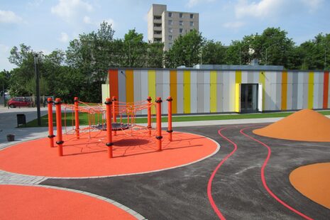 Das Gebäude des Quartiers- und Jugendzentrum Auerberg. Im Vordergrund der Spielplatz mit Klettergerüst.