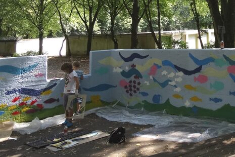 Malende Kinder vor einer bunten Wand