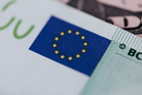 Primer plano de la bandera europea con las estrellas amarillas sobre fondo azul en un billete de euro