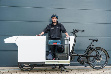 Ein junger Mann vor einem beladenen Lastenrad