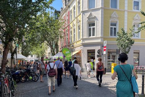 Auf dem Bild sind Menschen zu sehen, die als Gruppe durch die Stadt laufen. Im Hintergrund Gründerzeithäuser.