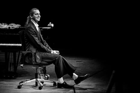 Foto in bianco e nero di Hagen Rether sullo sgabello del pianoforte